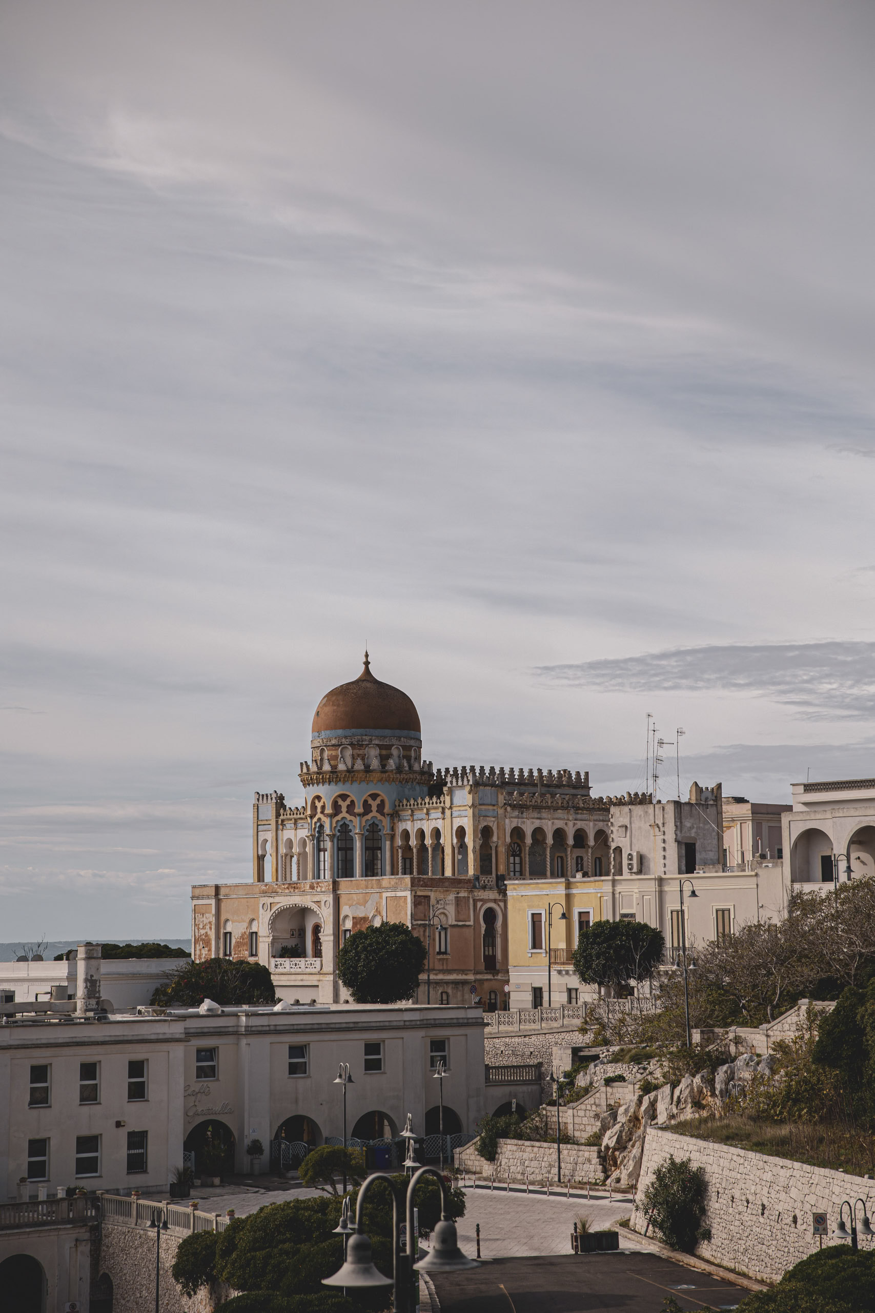Elegantes historisches Gebäude mit Kuppeldach und kunstvoller Architektur, thronend auf einer felsigen Landschaft, mit Blick auf einen wolkigen Himmel und einem Blick auf das Meer im Hintergrund. © Fotografie Tomas Rodriguez