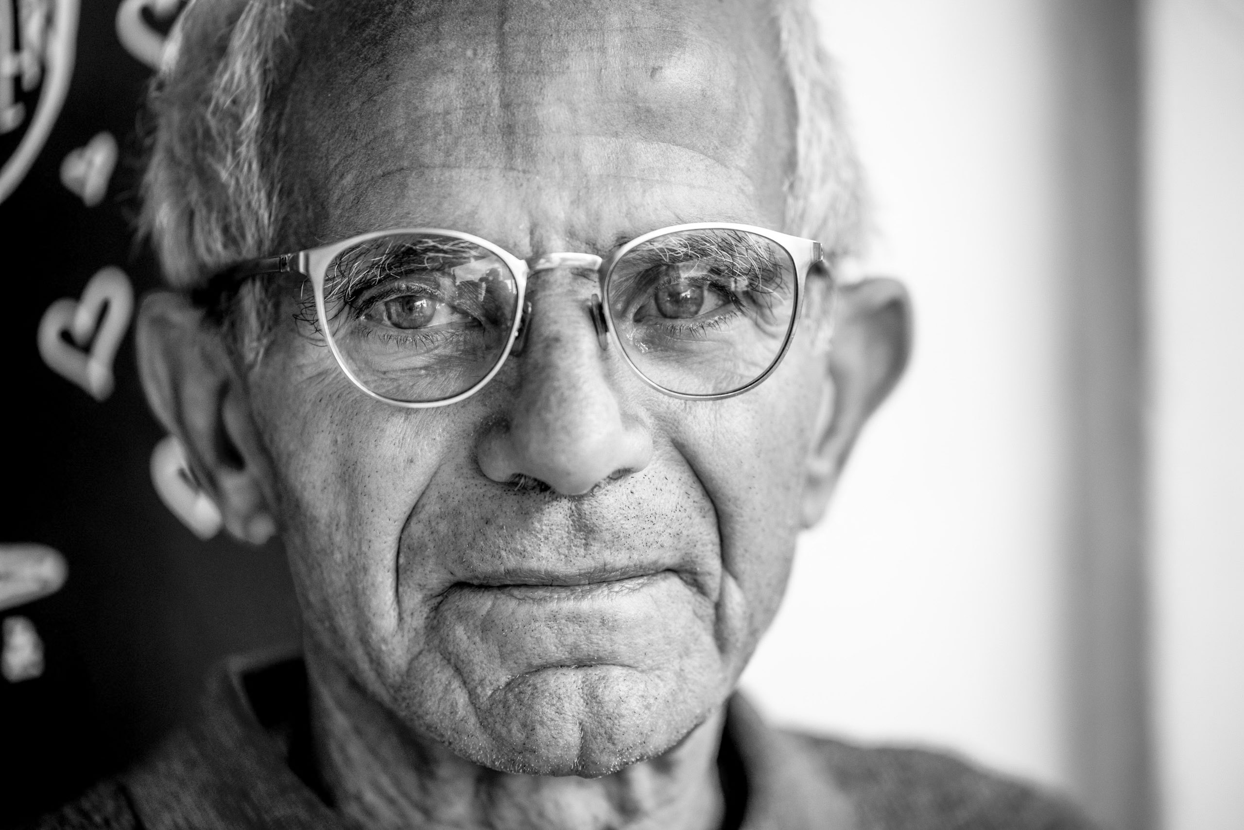 Nahaufnahme eines älteren Mannes mit nachdenklichem Gesichtsausdruck und Brille auf einem Schwarzweißfoto. © Fotografie Tomas Rodriguez
