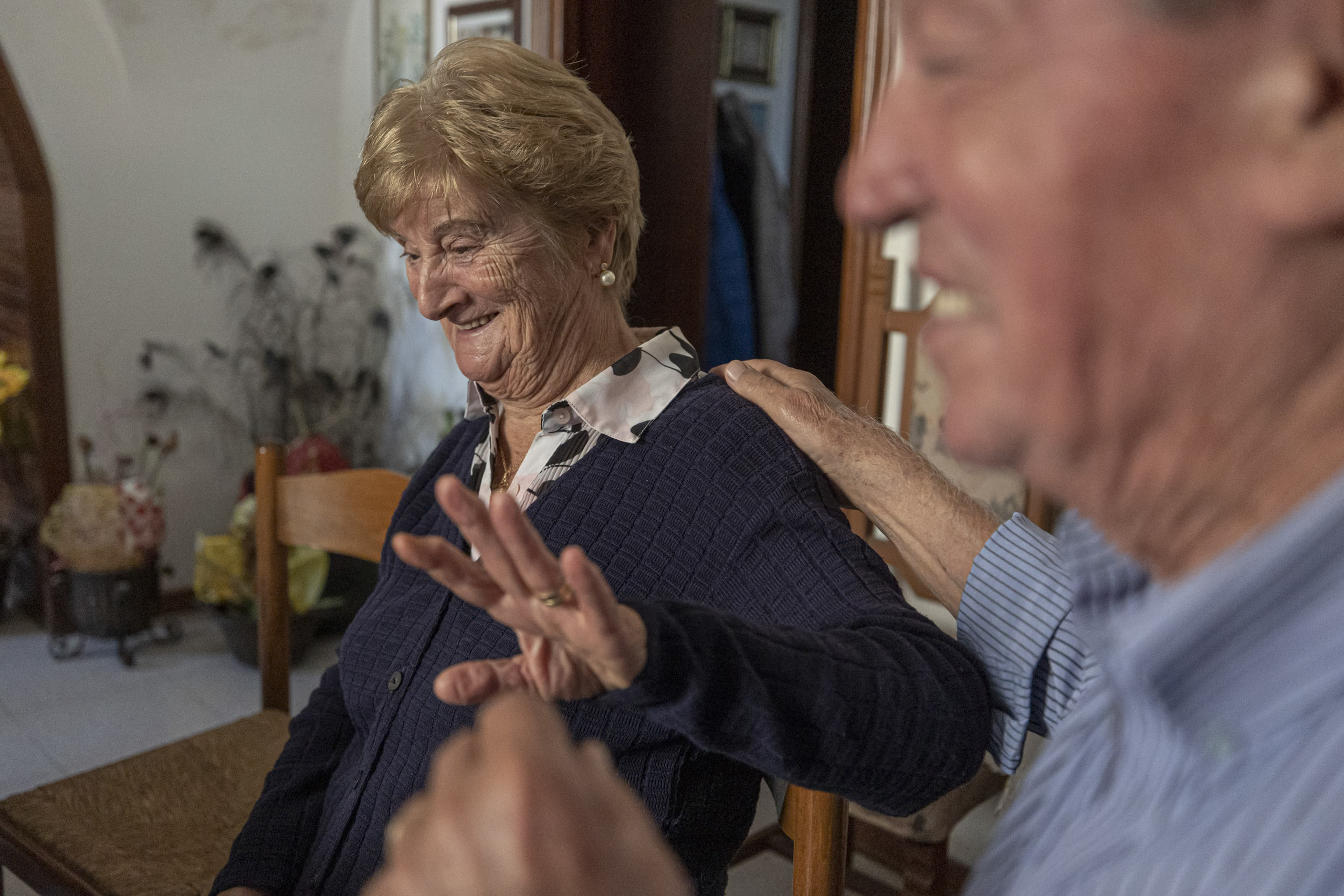 Ein fröhliches älteres Paar teilt einen unbeschwerten Moment. Die Frau lächelt strahlend, während sie mit dem teilweise sichtbaren Mann neben ihr interagiert, der lacht. © Fotografie Tomas Rodriguez
