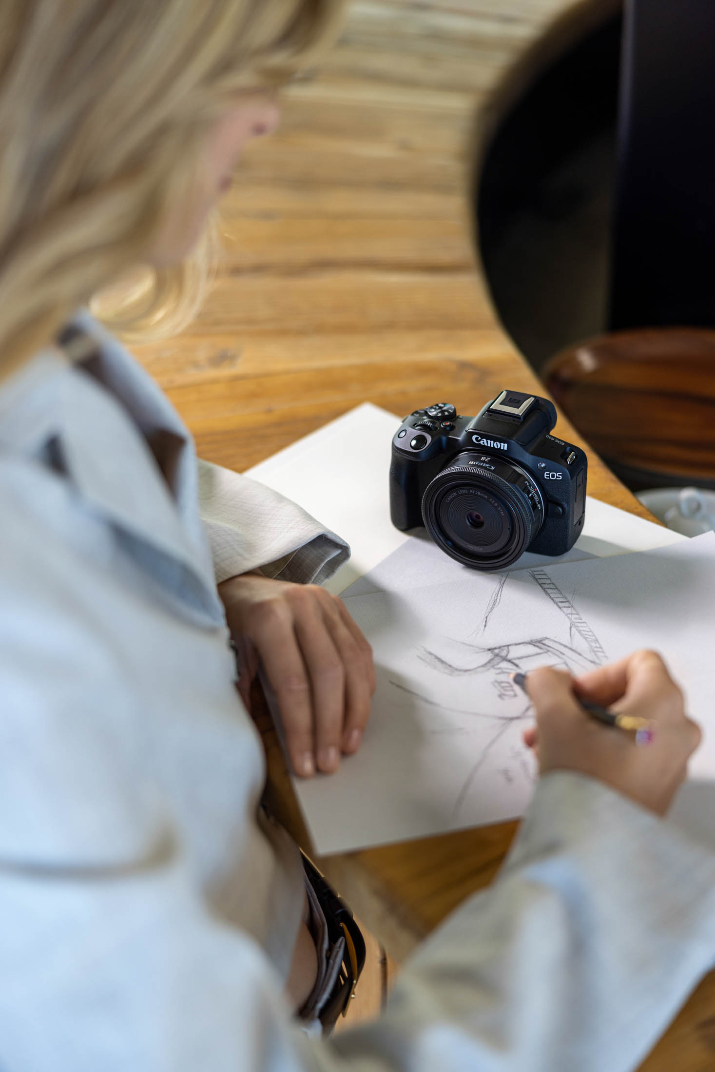Eine Frau macht eine Skizze auf Papier, vor ihr auf dem Tisch steht eine Canon-Kamera im Fokus. © Fotografie Tomas Rodriguez
