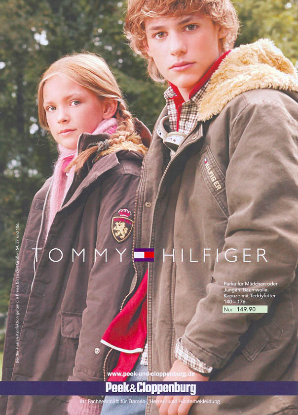 Eine Zeitschriftenanzeige zeigt ein junges Mädchen und einen Jungen in Wintermänteln von Tommy Hilfiger, die im Freien mit Bäumen im Hintergrund posieren. Der Junge steht etwas hinter dem Mädchen und beide blicken in die Kamera. © Fotografie Tomas Rodriguez