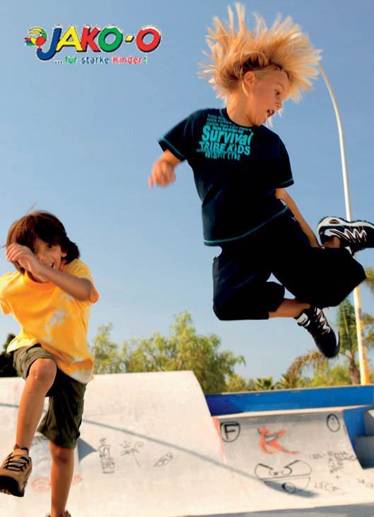 Zwei Kinder in einem Skatepark: eines springt energisch mit wehendem Haar, das andere duckt sich und bedeckt seinen Kopf mit einem Cowboyhut. Leuchtende Farben und verspielte Atmosphäre. © Fotografie Tomas Rodriguez