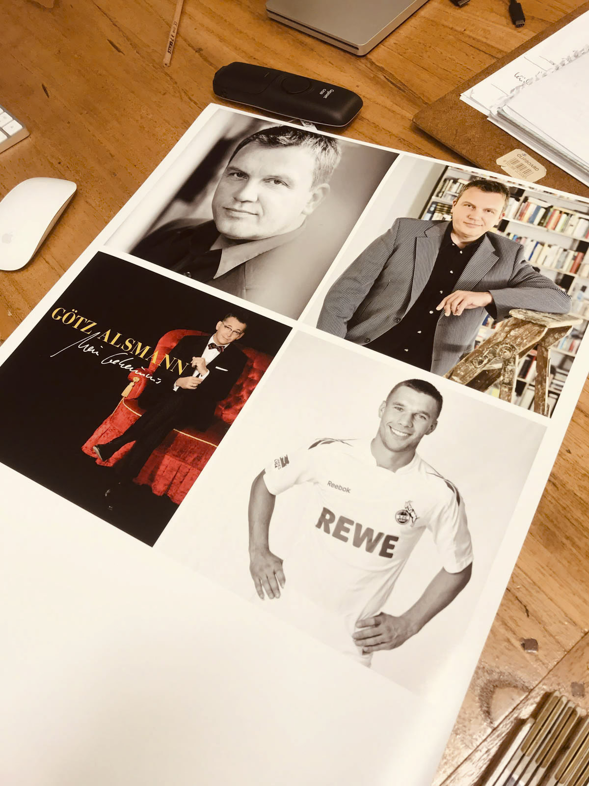 Ein Poster mit vier Fotos desselben Mannes in unterschiedlichen Situationen: eines in Schwarzweiß im Anzug, eines im grauen Anzug neben einem Bücherregal, eines im Smoking mit Mikrofon und eines im Fußballtrikot. Das Poster liegt auf einem Holzschreibtisch. © Fotografie Tomas Rodriguez