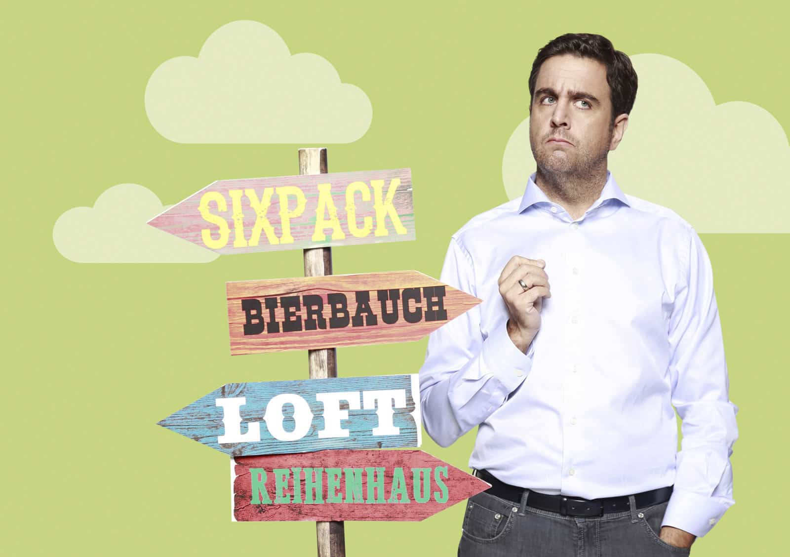 Ein Mann in weißem Hemd steht nachdenklich und hält sein Kinn neben einem Pfosten mit vier bunten Pfeilen. Die Pfeile zeigen nach links auf „SIXPACK“ und „BIERBAUCH“ und nach rechts auf „LOFT“ und „REIHENHAUS“. Der Hintergrund ist hellgrün mit weißen Wolken. © Fotografie Tomas Rodriguez