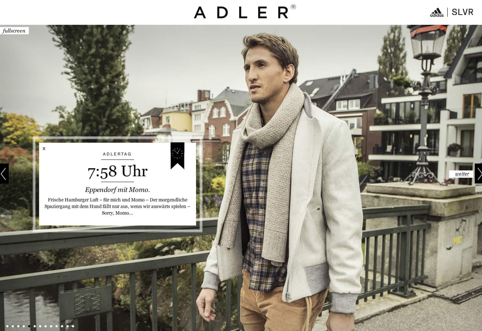 Ein Mann, der eine legere beige Jacke, einen grauen Schal und ein kariertes Hemd trägt, steht auf einer Brücke mit Wohnhäusern und einem grünen Park im Hintergrund. Die Texteinblendung zeigt „7:58 Uhr“ und beschreibt eine Morgenroutine mit Hamburg und Kaffee. © Fotografie Tomas Rodriguez