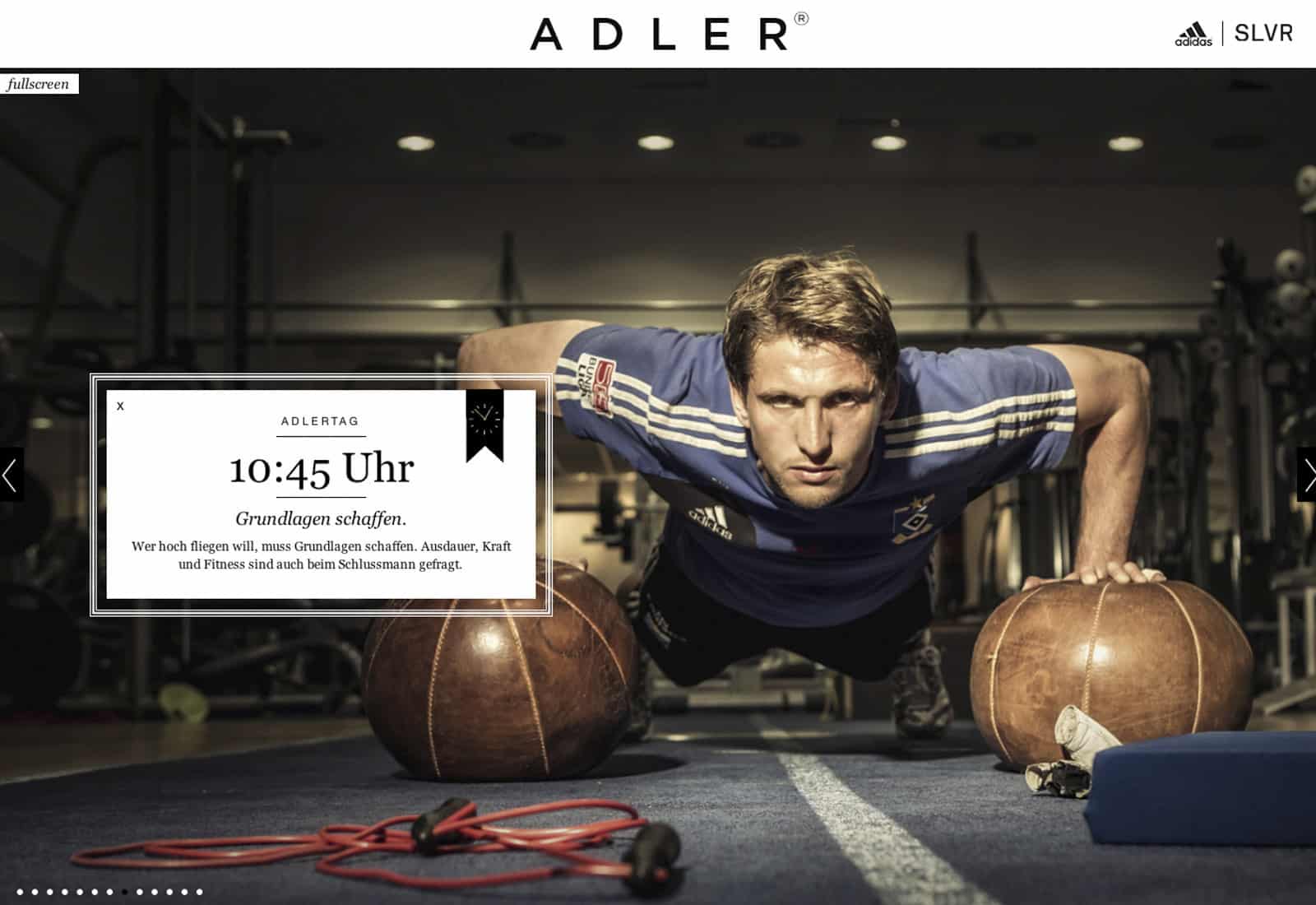 Eine Person im blauen Sporttrikot macht in einem Fitnessstudio Liegestütze und stützt sich dabei auf zwei Medizinbälle. Eine Bildunterschrift links zeigt einen Zeitplan: „10:45 Uhr – Grundlagen schaffen“. Im Hintergrund sind Fitnessgeräte verstreut. © Fotografie Tomas Rodriguez