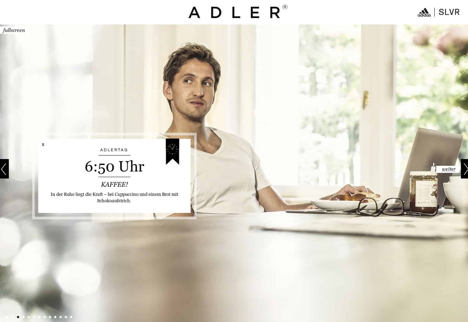 Ein Mann sitzt mit Laptop und Tasse Kaffee an einem Tisch und blickt leicht zur Seite. Auf dem Bild steht „Adler“, „6:50 Uhr“ und „KAFFEE!“. Im Hintergrund ist ein heller Innenraum mit Fenstern zu sehen, die Tageslicht hereinlassen. © Fotografie Tomas Rodriguez