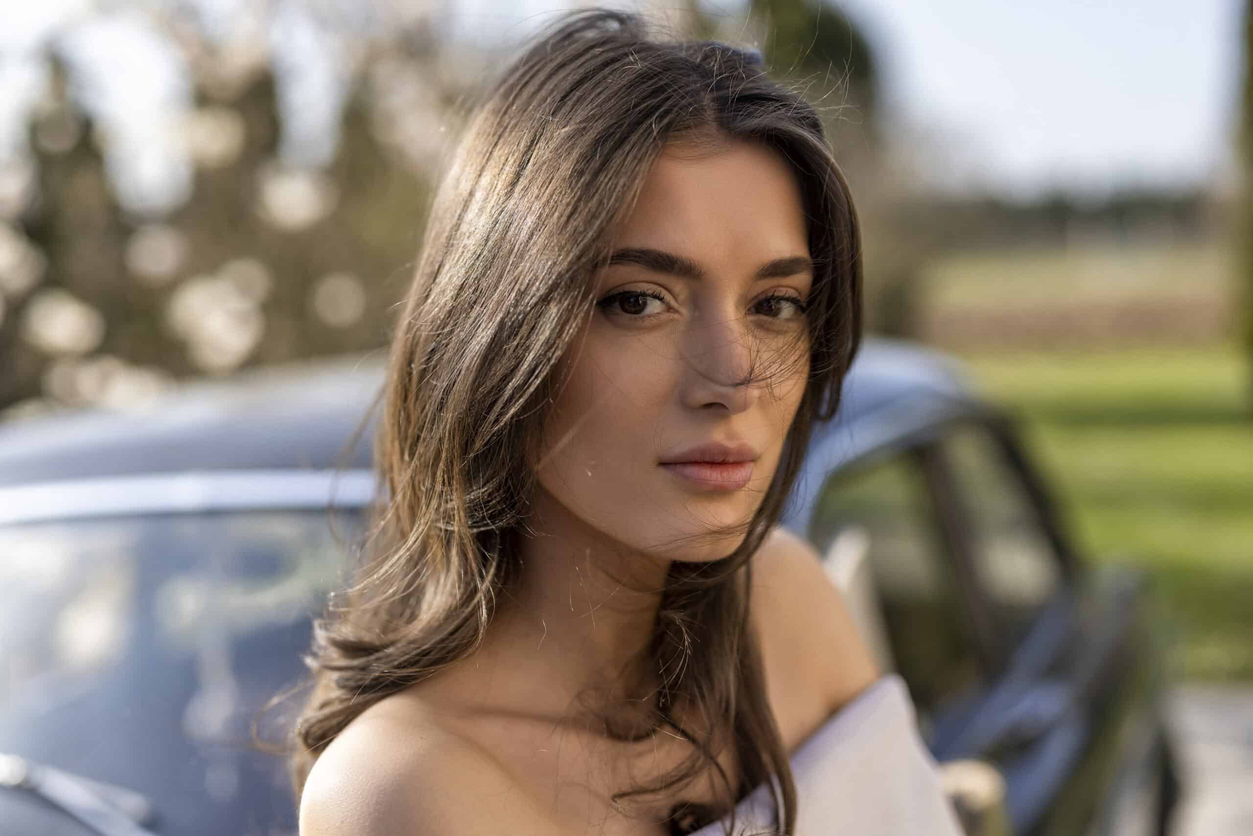 Portrait einer Frau vor einem Oldtimer im grünen