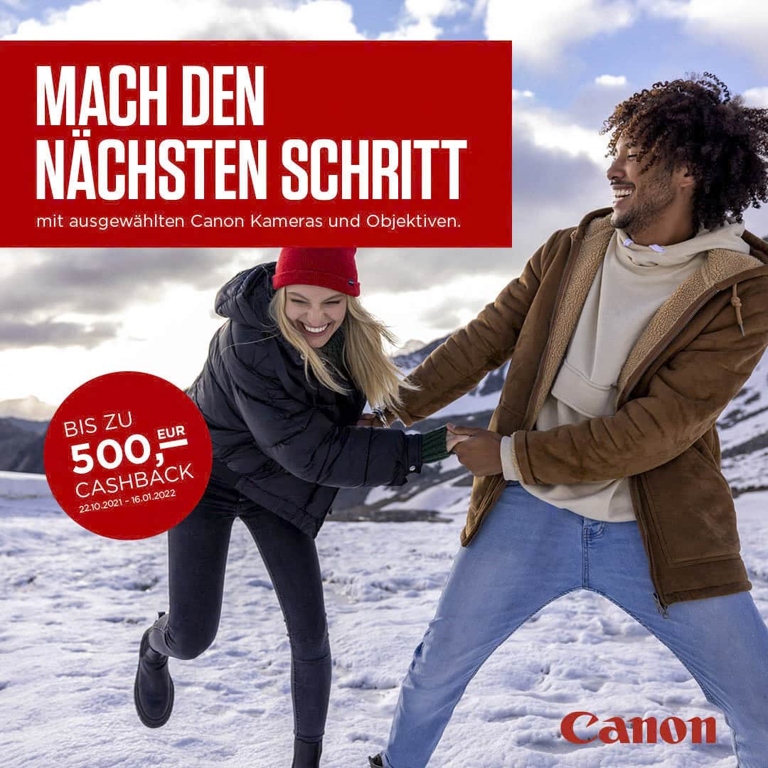 Ein Mann und eine Frau spielen fröhlich im Schnee vor einer Bergkulisse. Der Text lautet „MACH DEN NÄCHSTEN SCHRITT“ und erwähnt Cashback-Angebote für Canon Kameras und Objektive vom 22.10.2021 bis 16.01.2022. In der Ecke befindet sich das Canon Logo. © Fotografie Tomas Rodriguez