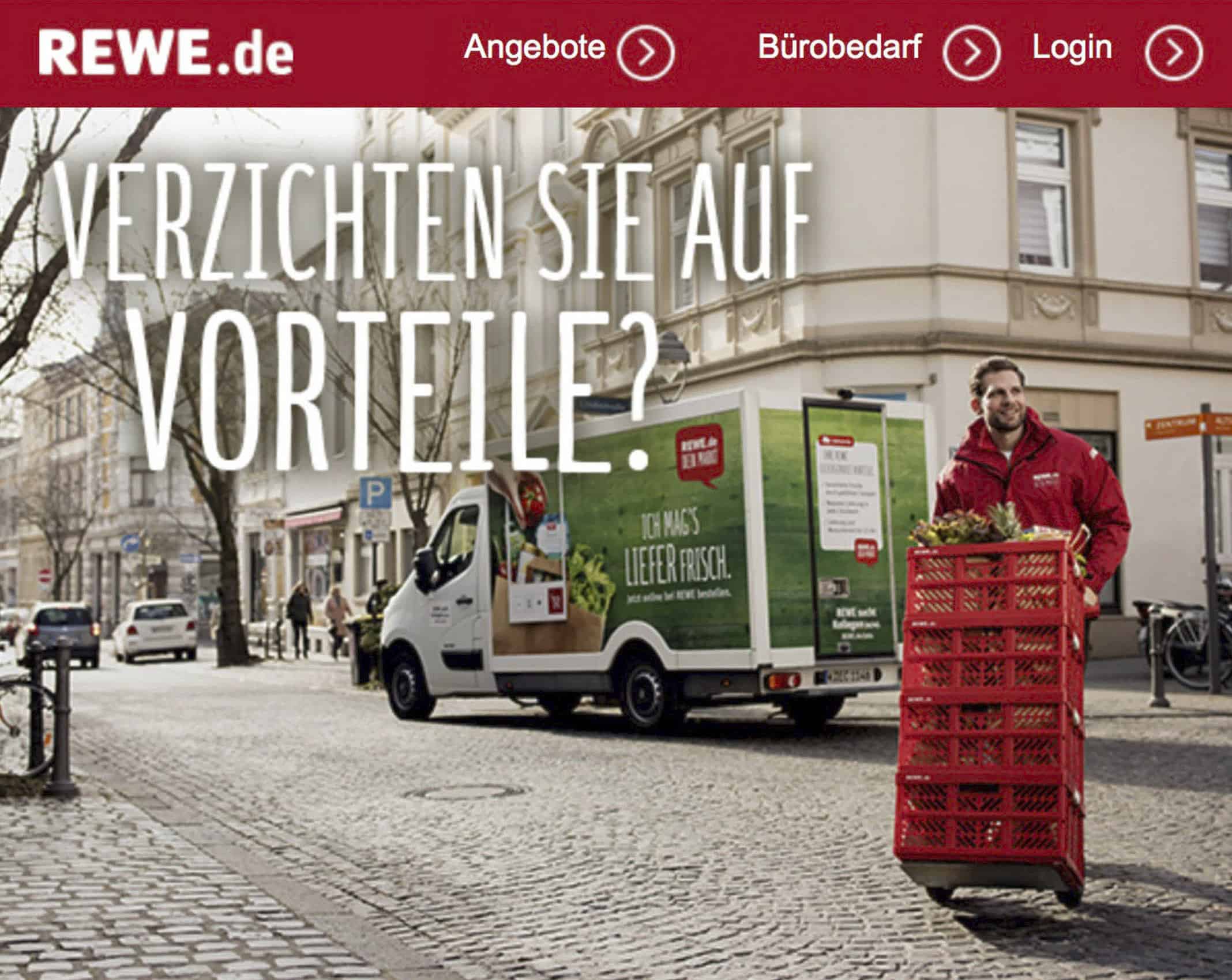 Ein Mann in roter Uniform schiebt einen Karren voller Kisten über eine Kopfsteinpflasterstraße. In der Nähe parkt ein Lieferwagen mit grün-roter Aufschrift. Oben sind der Text und die Navigationsleiste der REWE.de-Website zu sehen, mit einer großen Frage auf Deutsch. © Fotografie Tomas Rodriguez