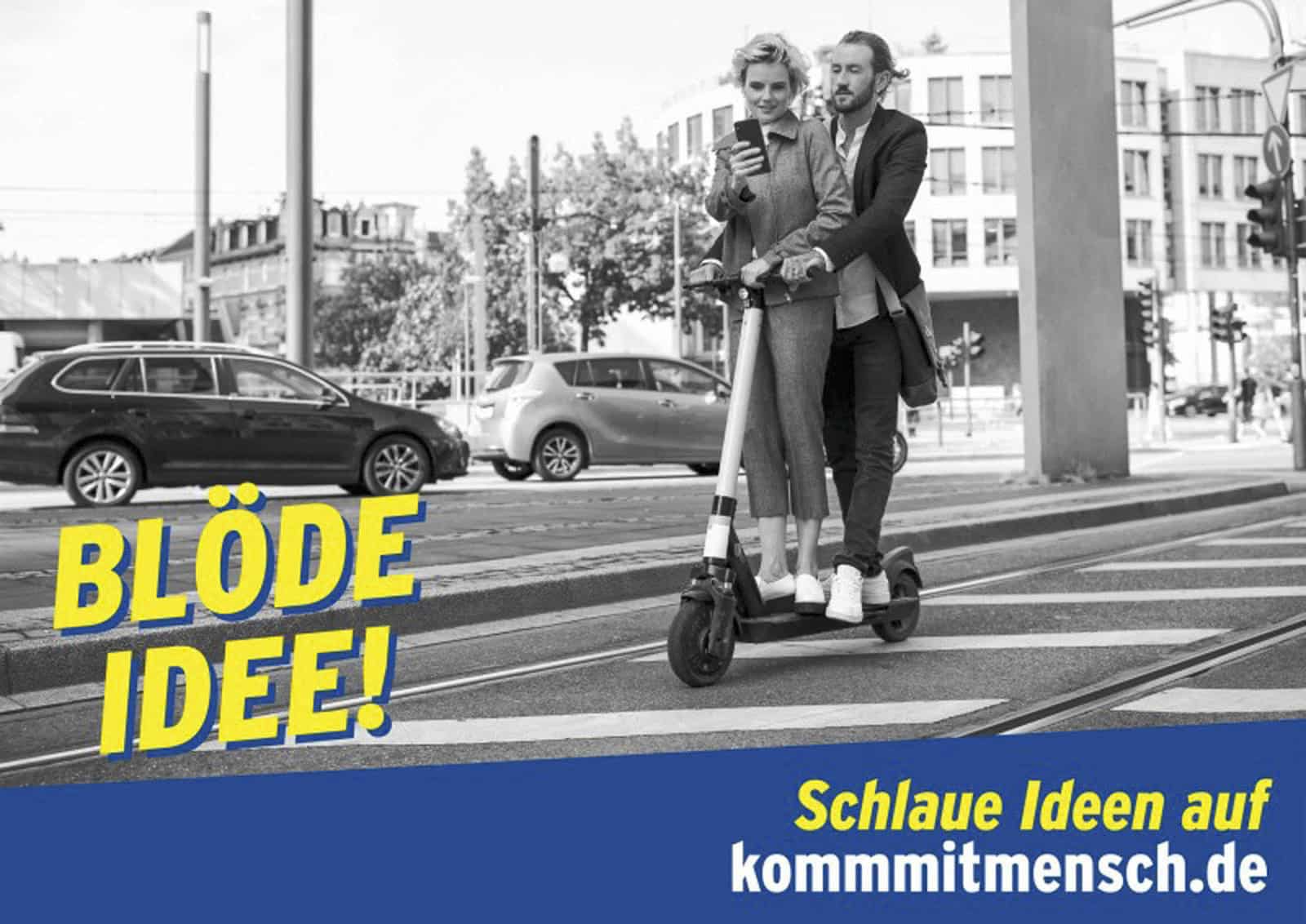Zwei Personen fahren zusammen auf einem Elektroroller auf einer Straße. Sie scheinen ein Telefon zu überprüfen. Der Textüberlagerungstext lautet „BLÖDE IDEE!“ mit einem blauen Banner mit der Aufschrift „Schlaue Ideen auf kommmitmensch.de“. Im Hintergrund sind Autos und Gebäude zu sehen. © Fotografie Tomas Rodriguez