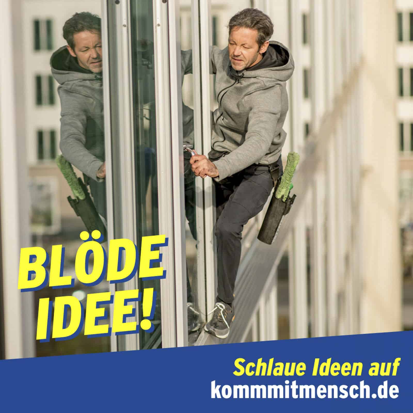 Ein Mann in Freizeitkleidung klettert an der Außenseite eines Gebäudes hoch und hält sich dabei an Fensterrahmen fest. Er scheint die Fenster zu putzen. Der Text lautet „BLÖDE IDEE!“ und „Schlaue Ideen auf kommmitmensch.de.“. © Fotografie Tomas Rodriguez