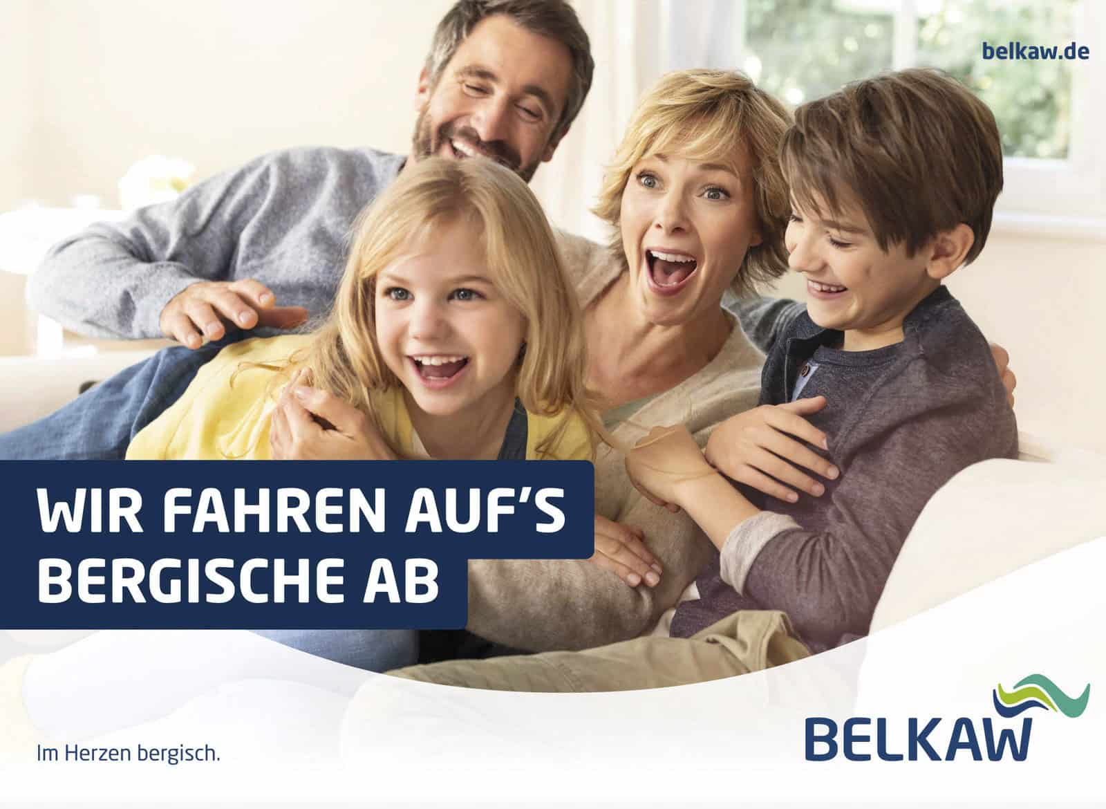 Eine fröhliche vierköpfige Familie, zwei Erwachsene und zwei Kinder, sitzt und lacht zusammen auf einem Sofa. Sie befinden sich in einem hellen Raum. Das Bild enthält den Text „Wir fahren auf’s Bergische ab“ und das Logo von BELKAW. © Fotografie Tomas Rodriguez