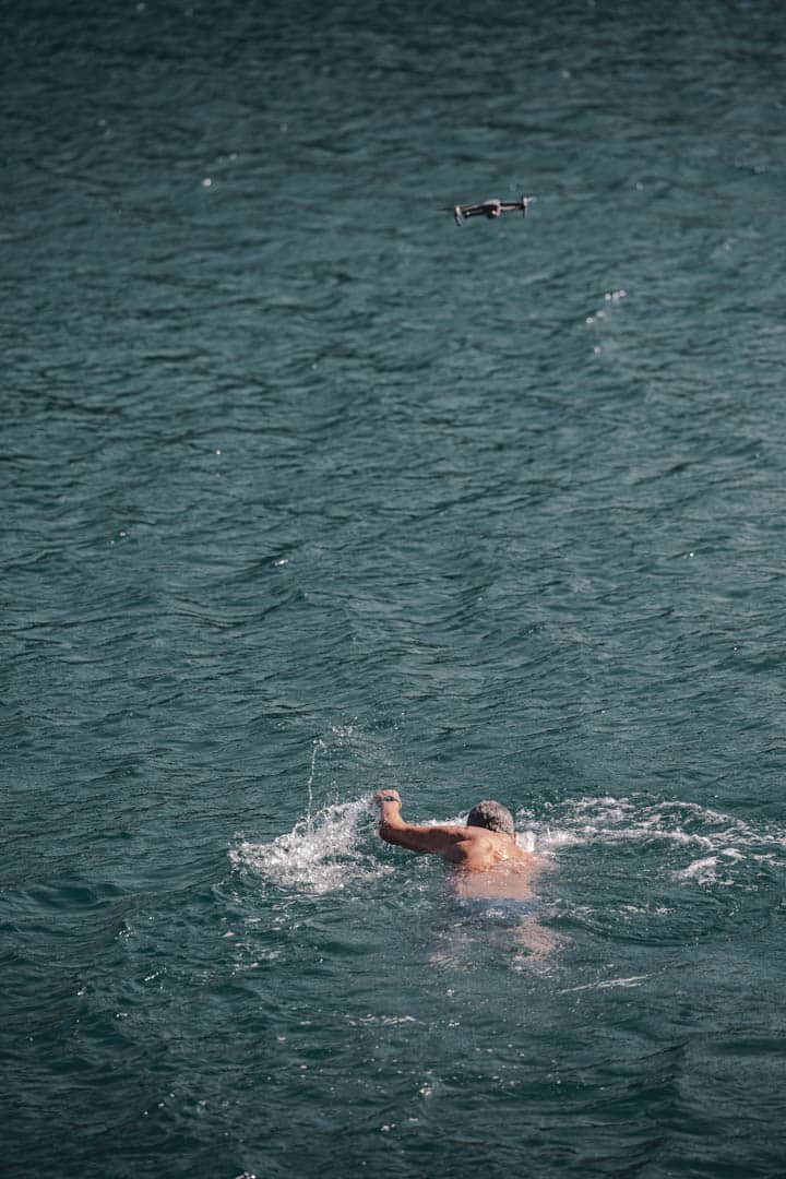 Eine Person schwimmt im Freistil im offenen Wasser, während eine Drohne über ihr schwebt und die Szene einfängt. Das Wasser ist tiefblau und leicht gekräuselt. © Fotografie Tomas Rodriguez