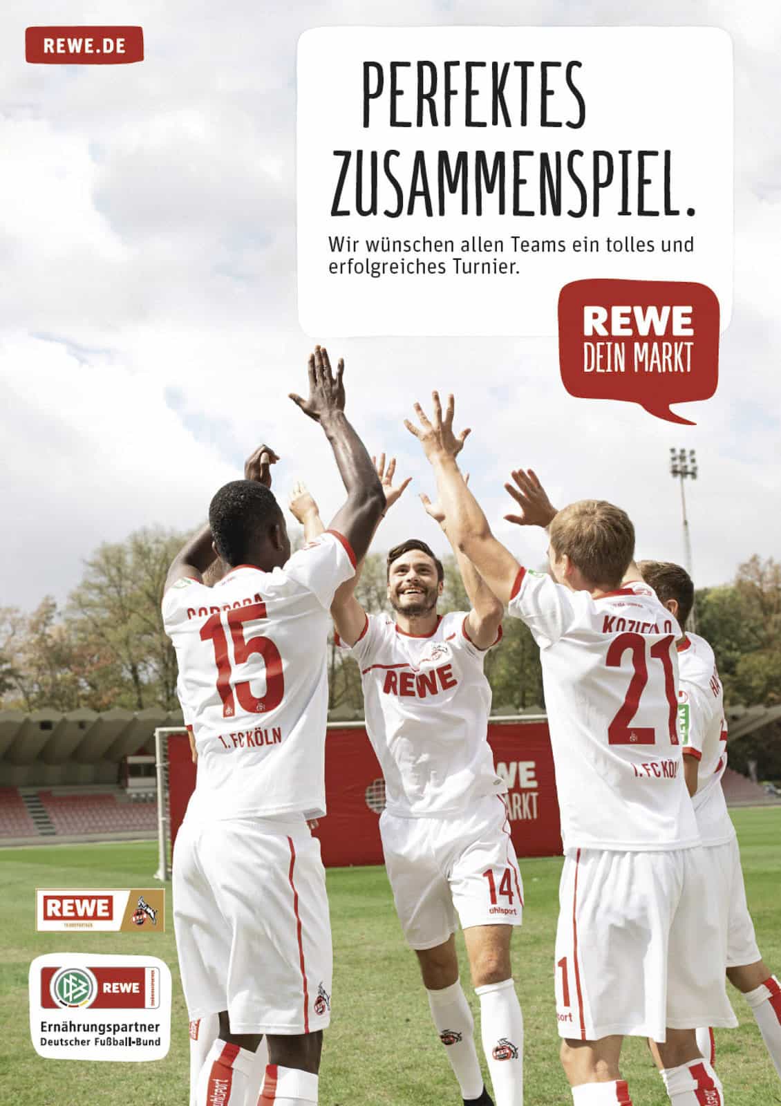 Vier männliche Fußballspieler in weißen REWE-Trikots jubeln und heben gemeinsam die Hände auf einem Fußballfeld und jubeln. Im Hintergrund sind Stadionplätze und Bäume zu sehen. Das Bild zeigt das REWE-Branding und deutschen Text. © Fotografie Tomas Rodriguez