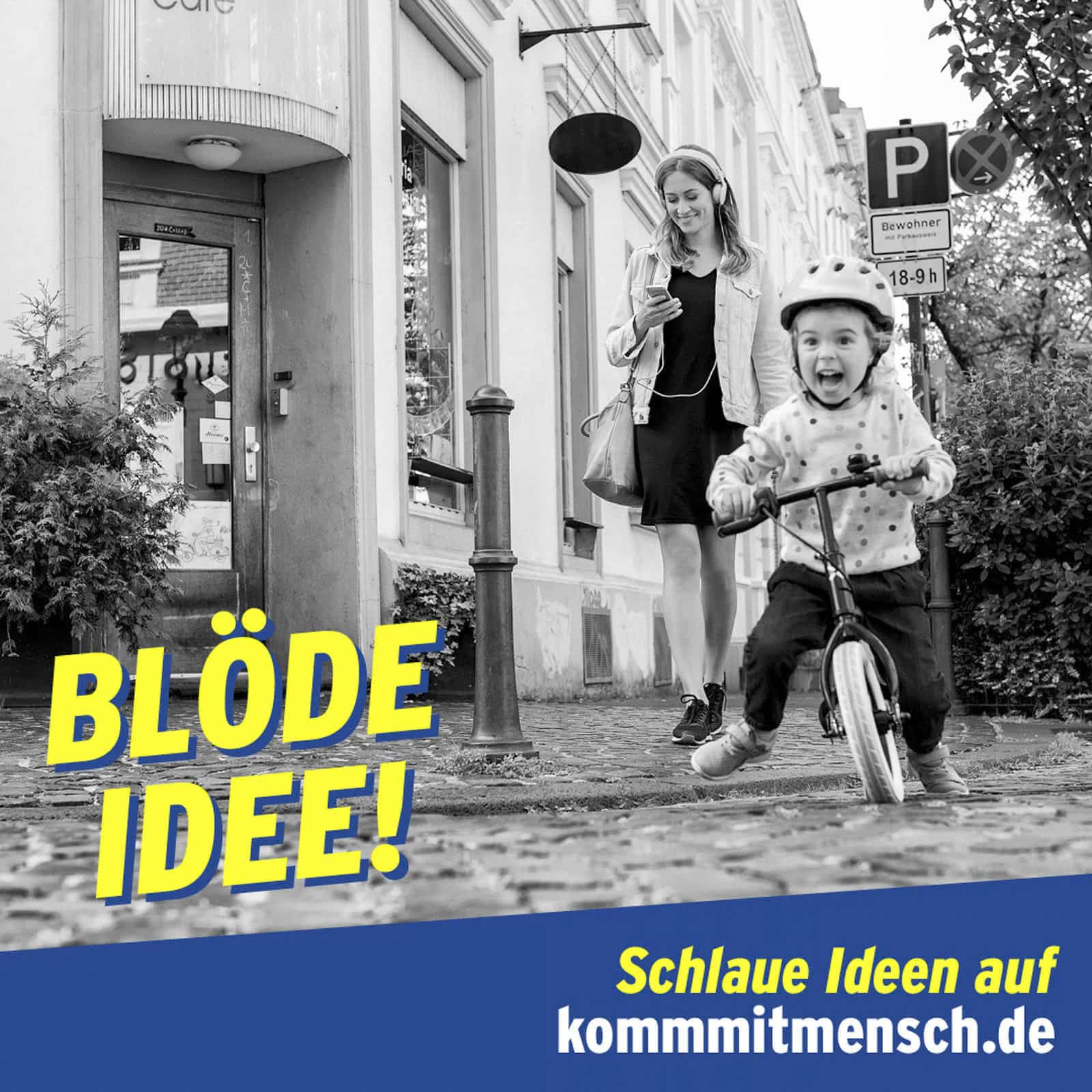 Eine Frau geht spazieren und schaut dabei auf ihr Handy. Vor ihr fährt ein kleiner Junge lächelnd mit dem Fahrrad auf einer nassen Kopfsteinpflasterstraße. Der Text lautet: "BLÖDE IDEE! Schlaue Ideen auf kommmitmensch.de". © Fotografie Tomas Rodriguez