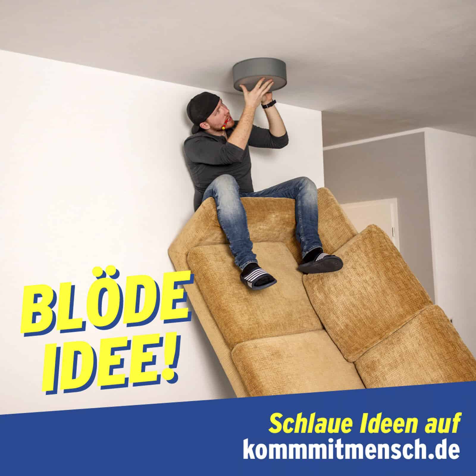 Ein Mann balanciert gefährlich auf gestapelten Couches, während er versucht, eine Deckenleuchte auszuwechseln. Der Text lautet "BLÖDE IDEE!" und "Schlaue Ideen auf kommmitmensch.de" auf einem blau-gelben Banner am unteren Rand. © Fotografie Tomas Rodriguez
