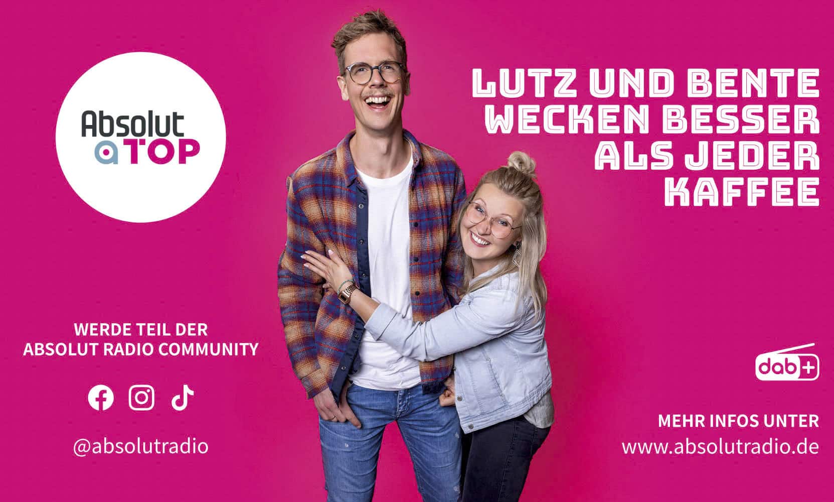 Zwei lächelnde junge Erwachsene, ein Mann und eine Frau, stehen lachend zusammen vor einem rosa Hintergrund. Der Text auf Deutsch wirbt für das Radio "Absolut Top" und lautet: "Lutz und Bente wecken besser als jeder Kaffee. © Fotografie Tomas Rodriguez