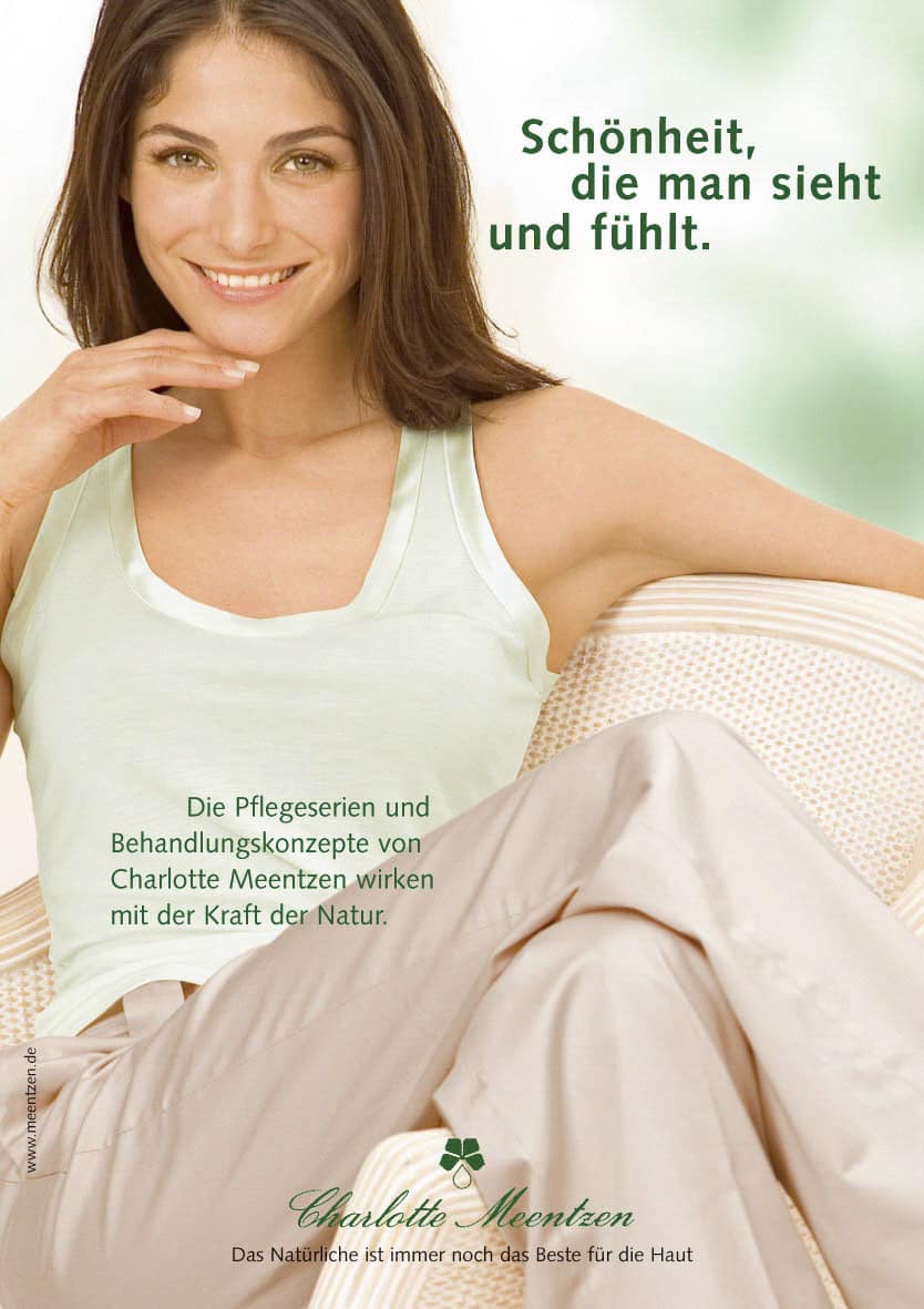 Eine lächelnde Frau mit langen braunen Haaren sitzt auf einem hellen Stuhl und trägt ein mintgrünes Tanktop und eine beigefarbene Hose. Neben ihr ist ein deutscher Text über Charlotte Meentzen Hautpflege zu lesen. © Fotografie Tomas Rodriguez