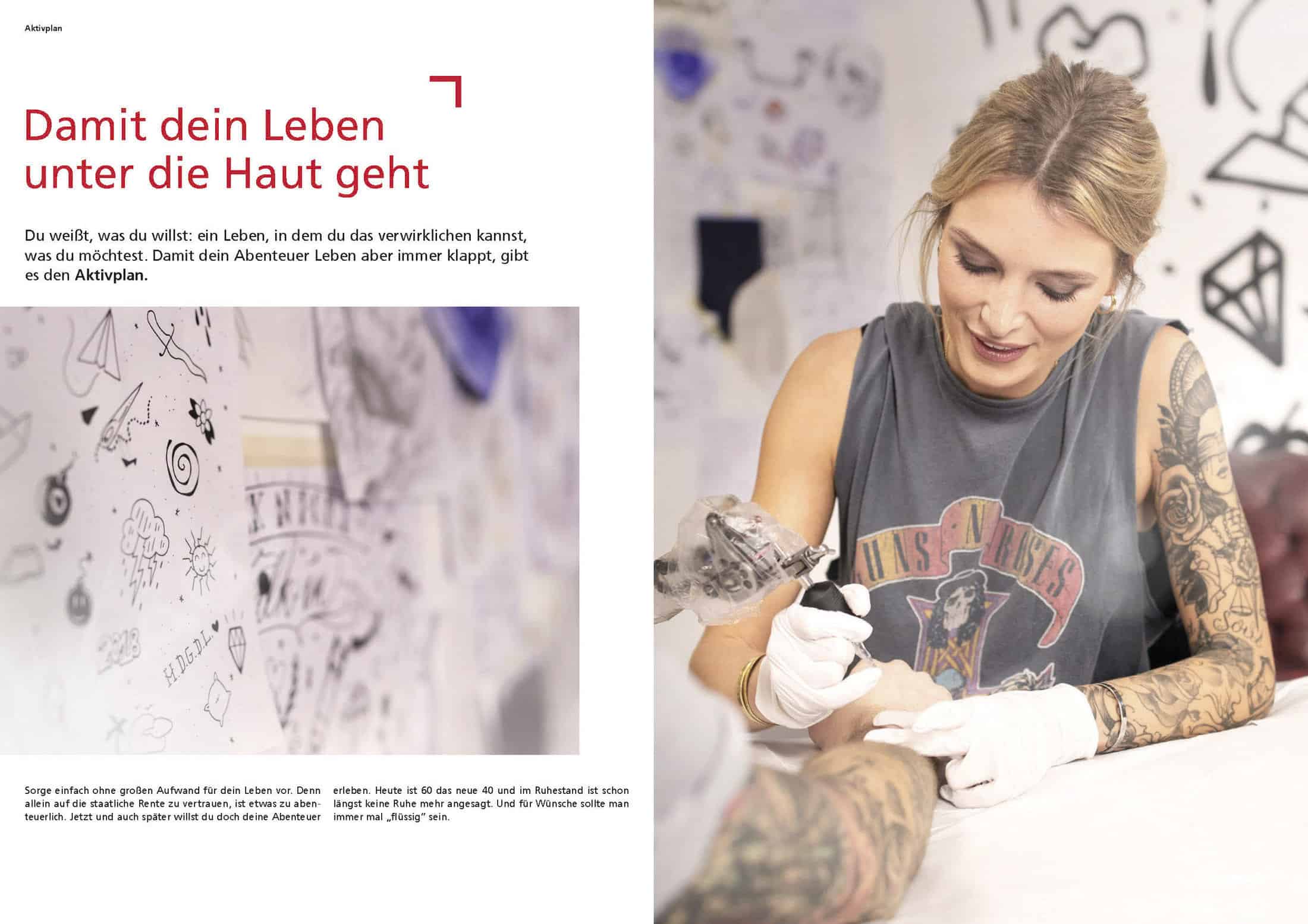 Eine lächelnde, tätowierte Frau mit Handschuhen und ärmellosem Hemd tätowiert den Arm einer Person in einem hellen Studio. Die linke Seite zeigt deutschen Text und eine weiße Wand, die mit Tattoo-Skizzen und Kritzeleien bedeckt ist. © Fotografie Tomas Rodriguez